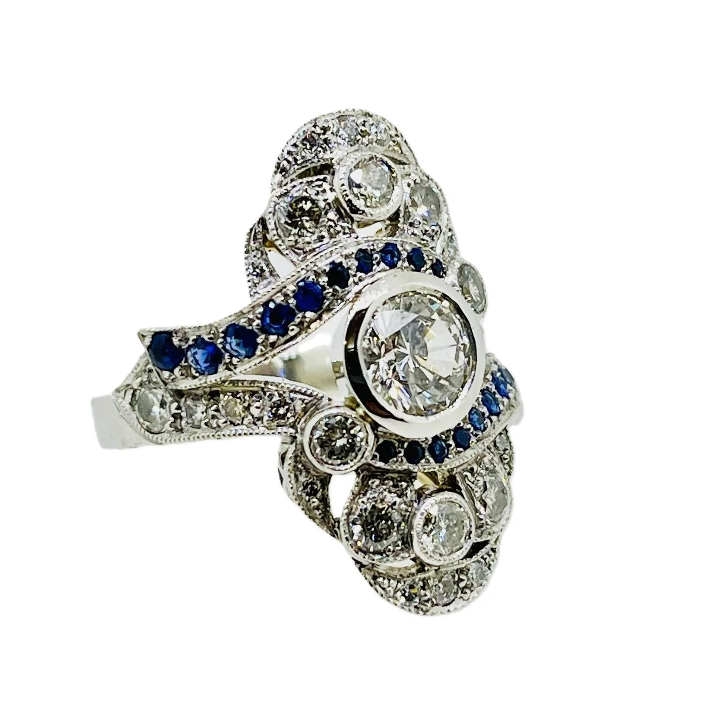 Platinum and white gold dress ring with large central diamond, blue sapphires and white smaller diamonds, and intricate swirl design reminiscent of art deco design