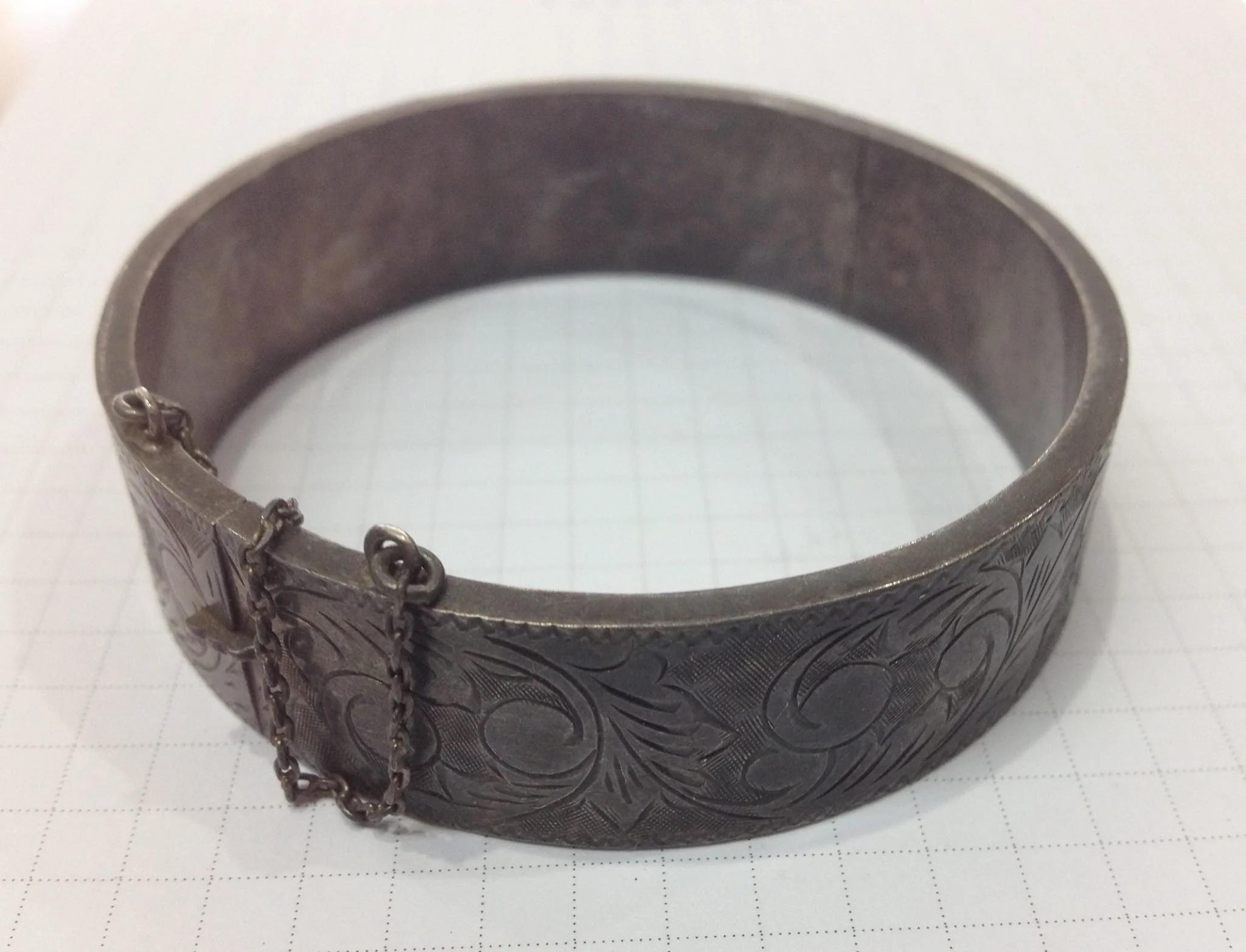 Close-up of a dull silver bracelet with engraved patterns.