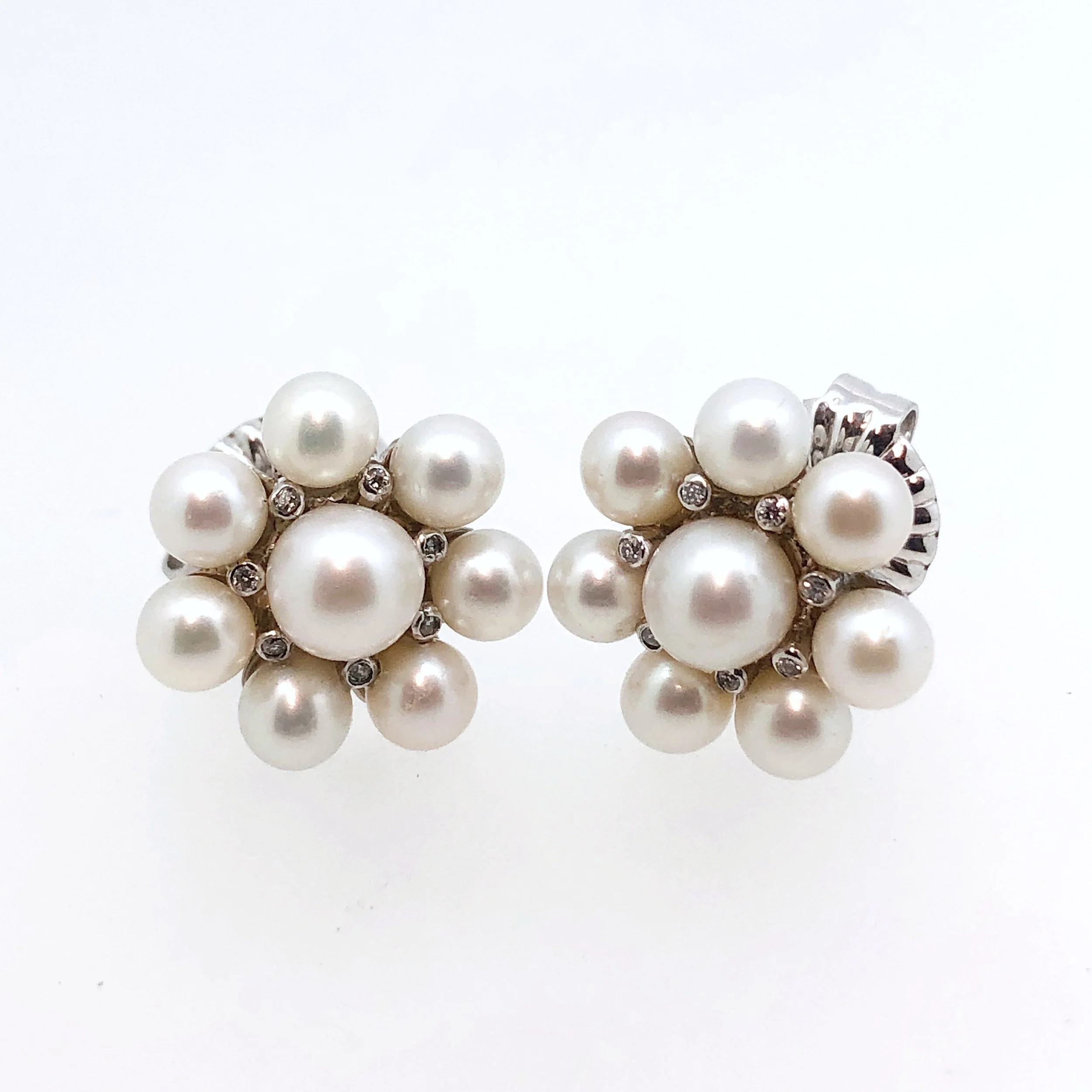 Close-up of pearl earrings with diamond accents. 