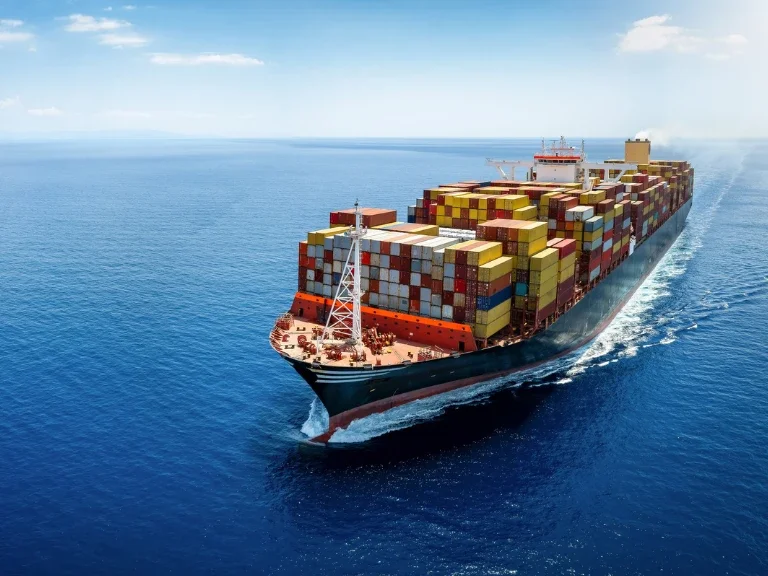 A large cargo ship sailing on the ocean, carrying numerous colorful shipping containers.