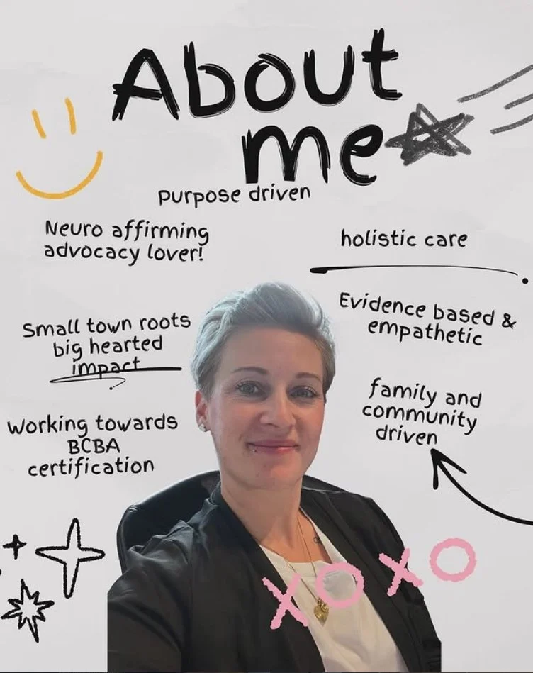A woman with short blonde hair taking a selfie in front of a whiteboard with handwritten notes and doodles about herself, including her purpose-driven, neuro-affirming advocacy, family and community focus, and goals like certification efforts.
