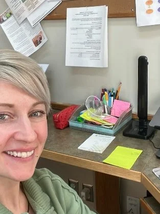 Office desk with papers, office supplies, and a woman smiling in the corner.