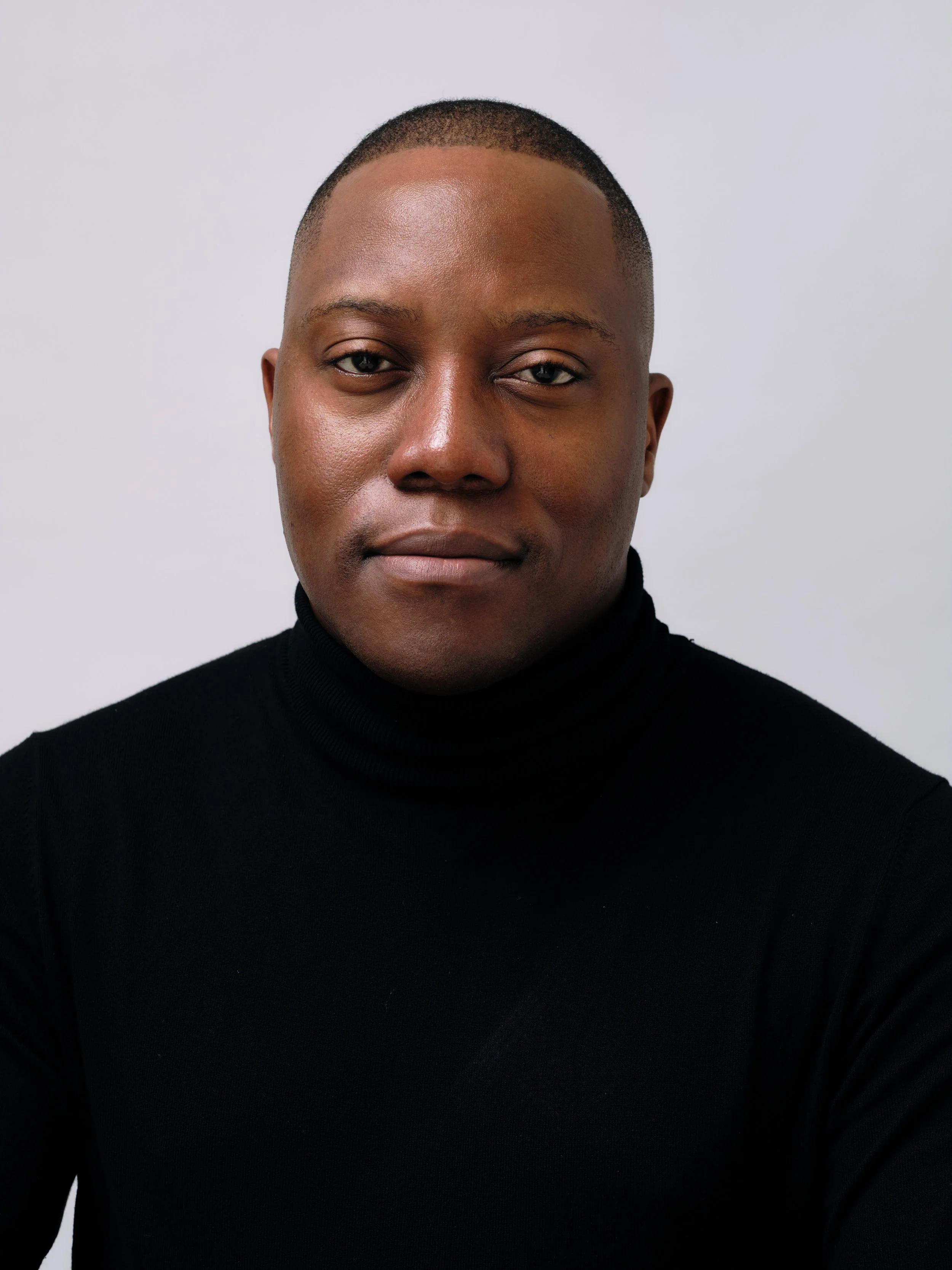 Headshot of Dr Xavier Mulenga, Melbourne psychiatrist, wearing a black turtleneck, against a plain white background.