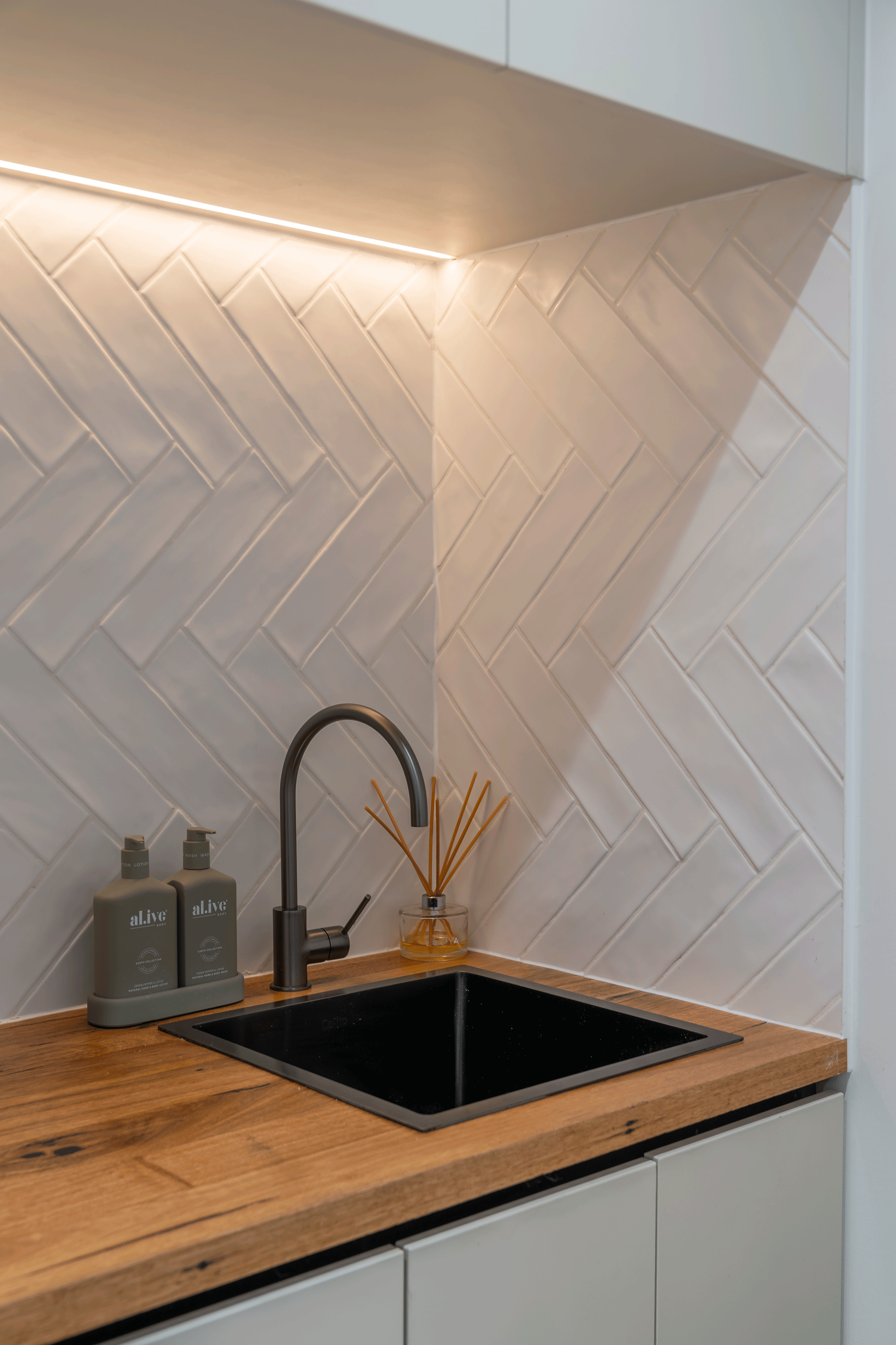 Wooden bench top in a laundry with white, herringbone layed subway tiles