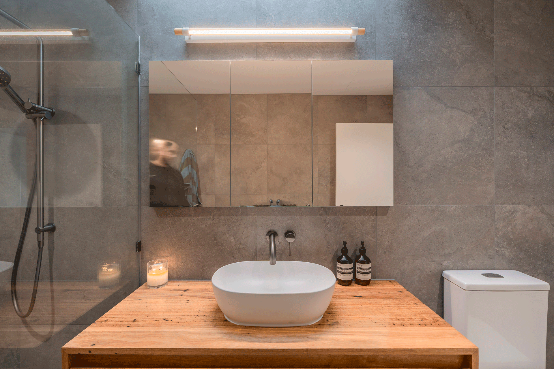 Grey stone tiles and warm timber vanity top in contemporary bathroom