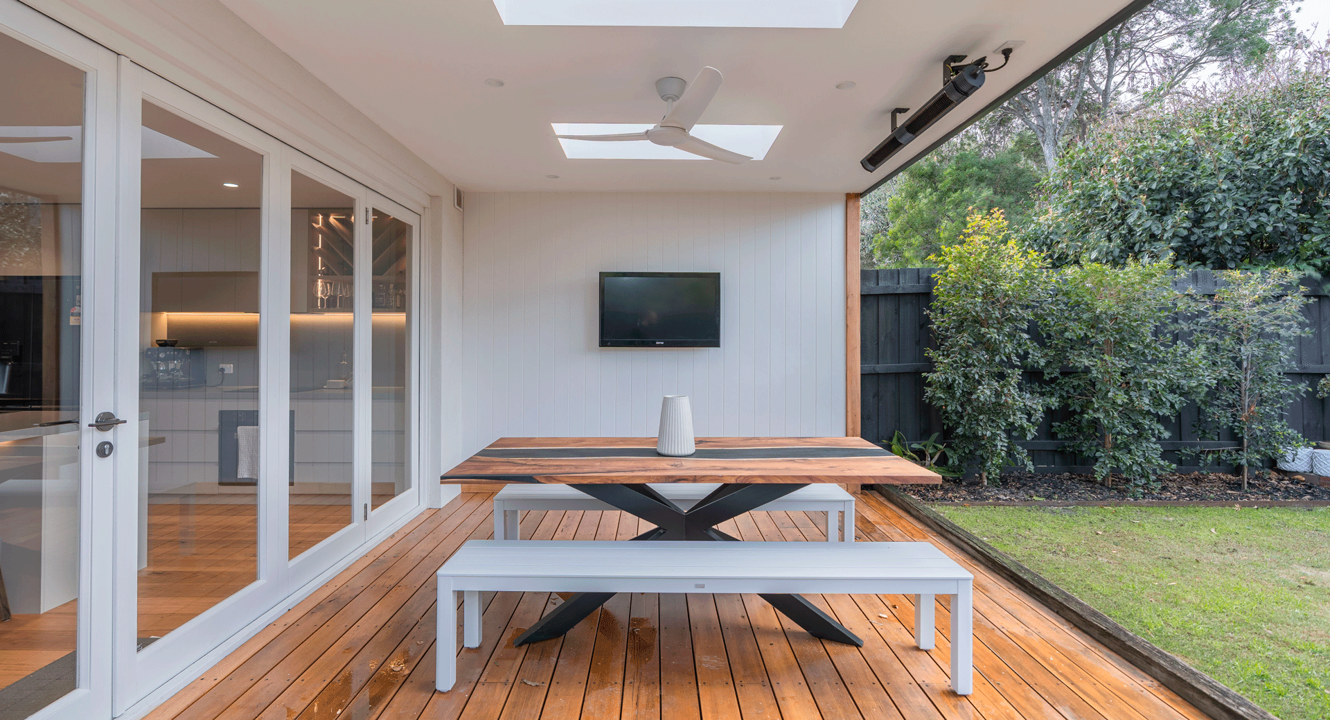 Timber deck floor in heated, covered outdoor area with contrasting white walls and french doors