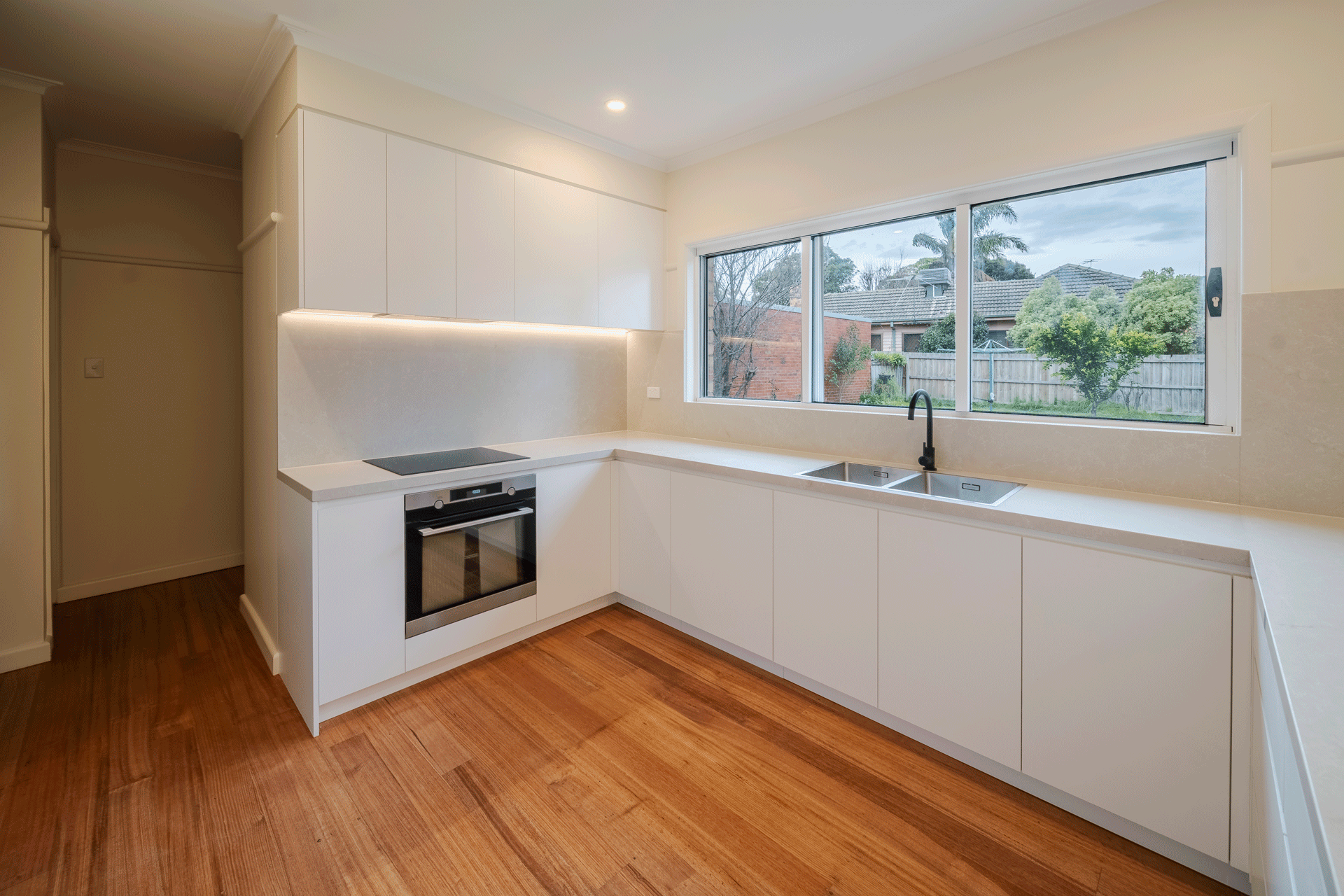 Warm timber floors in contrast to slick white cupboards in kitchen reno