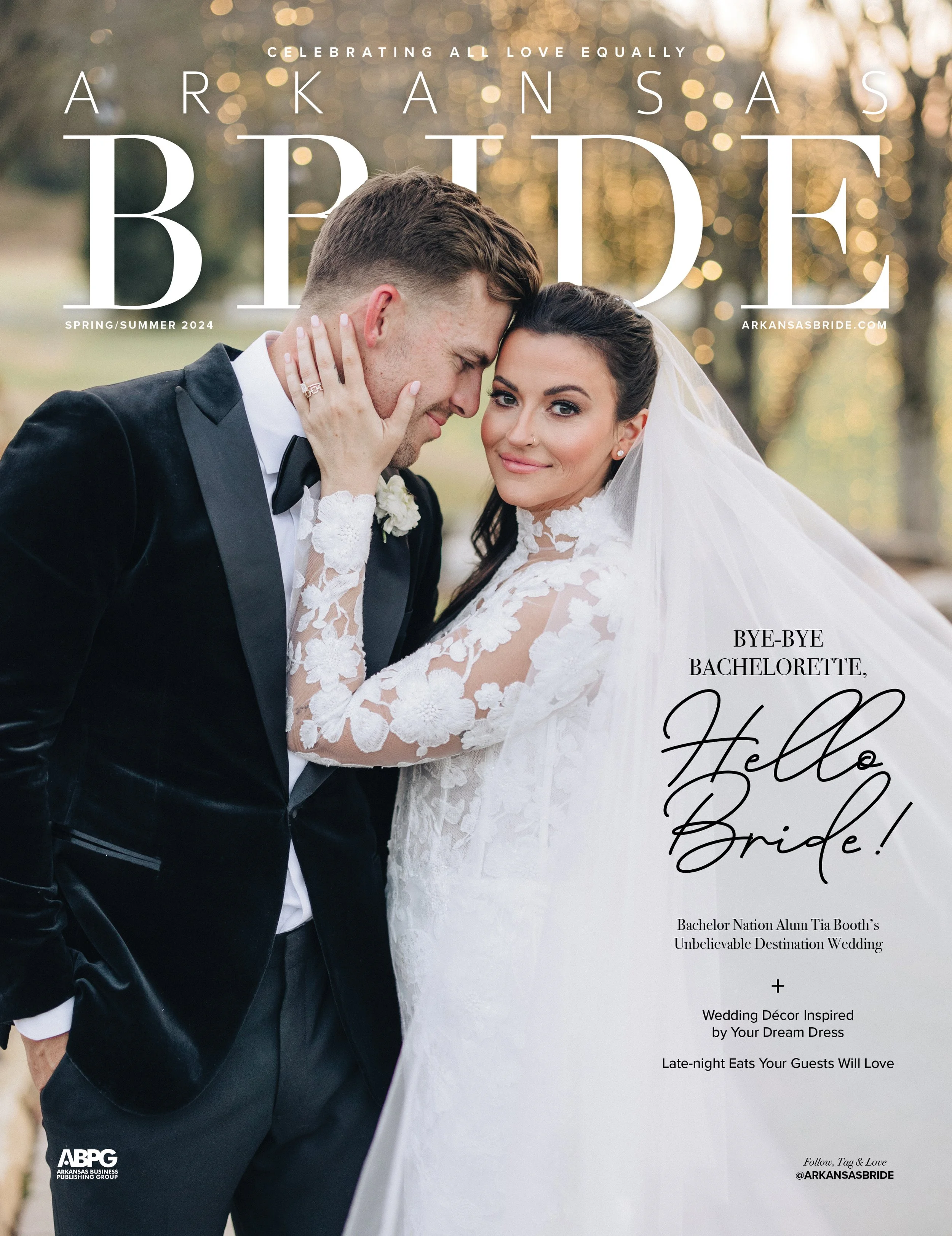 A bride and groom in wedding attire posing outdoors during sunset, with the groom wearing a black tuxedo and the bride in a white lace wedding dress and veil, smiling and touching foreheads.