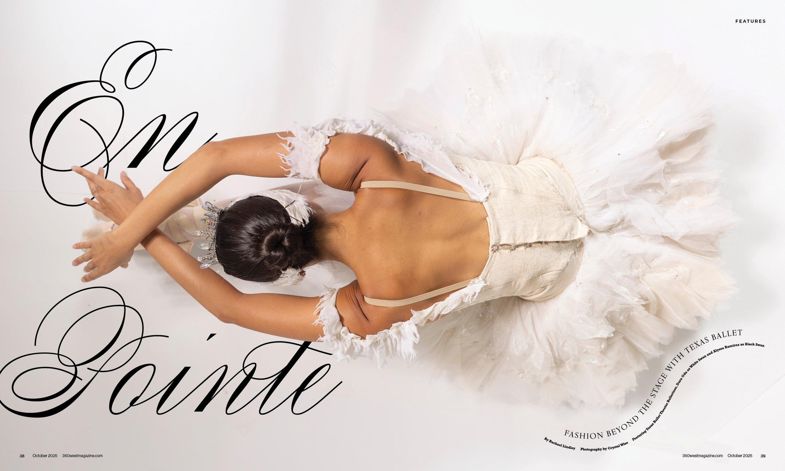 A ballerina in a white tutu and beige top, with her hair in a bun. She is lying face down on a white surface, reaching towards the top-left corner of the image, with a black swan tattoo on her arm.