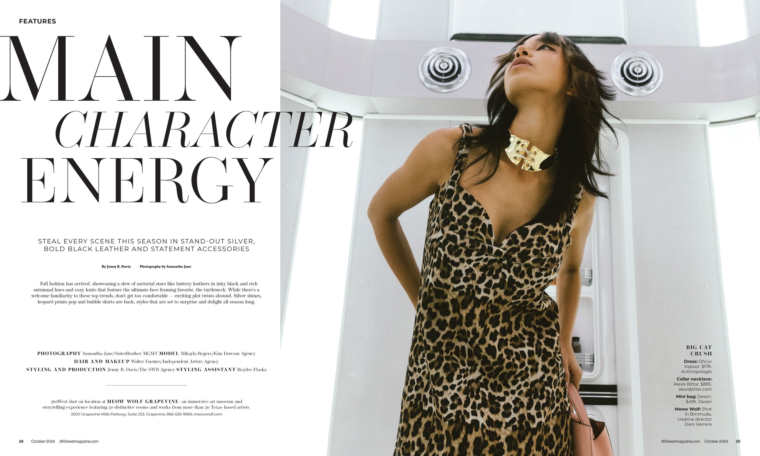 A woman with dark hair wearing a leopard print dress and a large gold statement necklace, standing in a white room with circular ceiling vents and a window.