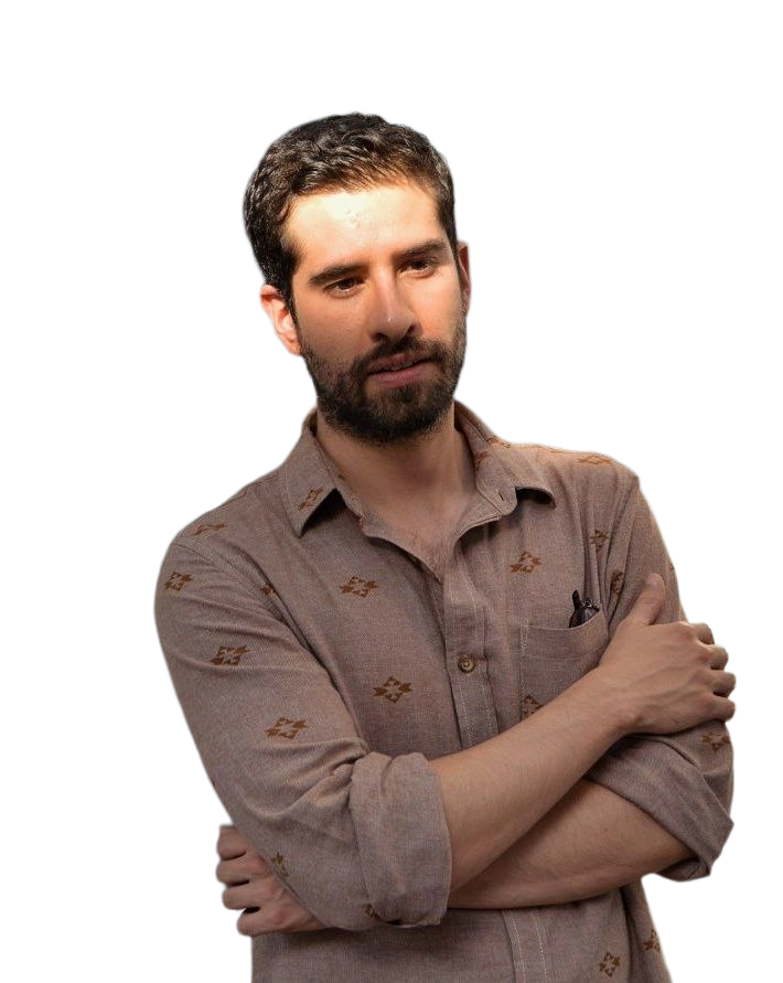 Hombre con barba, cabello corto, usando camisa de manga larga color beige con detalles, con los brazos cruzados, en actitud pensativa o reflexiva.