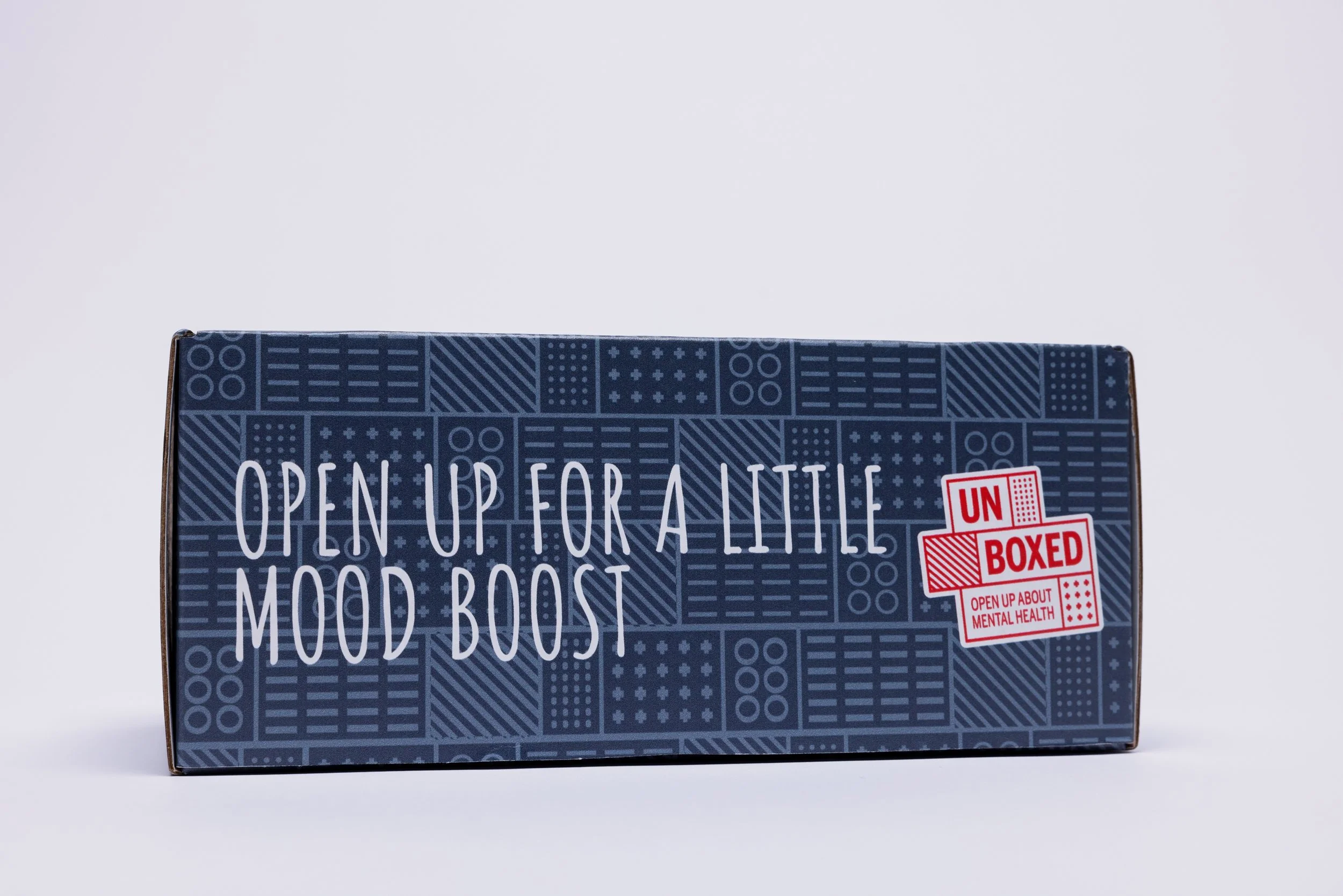 side of a box reading "Open up for a little mood boost" and a red and white logo next to it