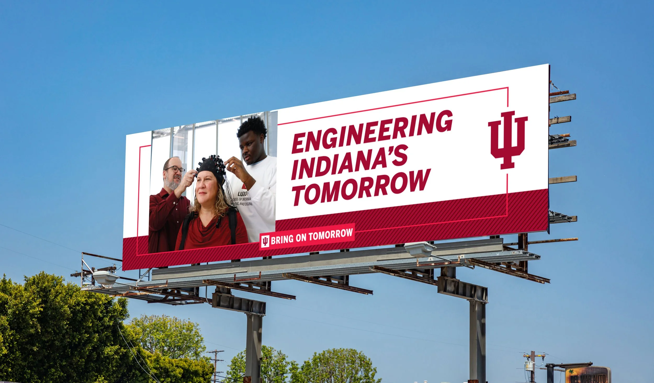 Billboard reading "Engineering Indiana's Tomorrow" with a large IU Trident on the right hand side and an image of a male professor and a male student adjusting a brain wave sensor cap on an adult female.