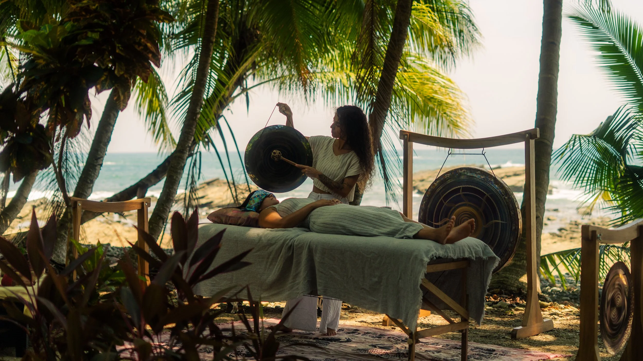 Yoselyn playing the gong on the beach