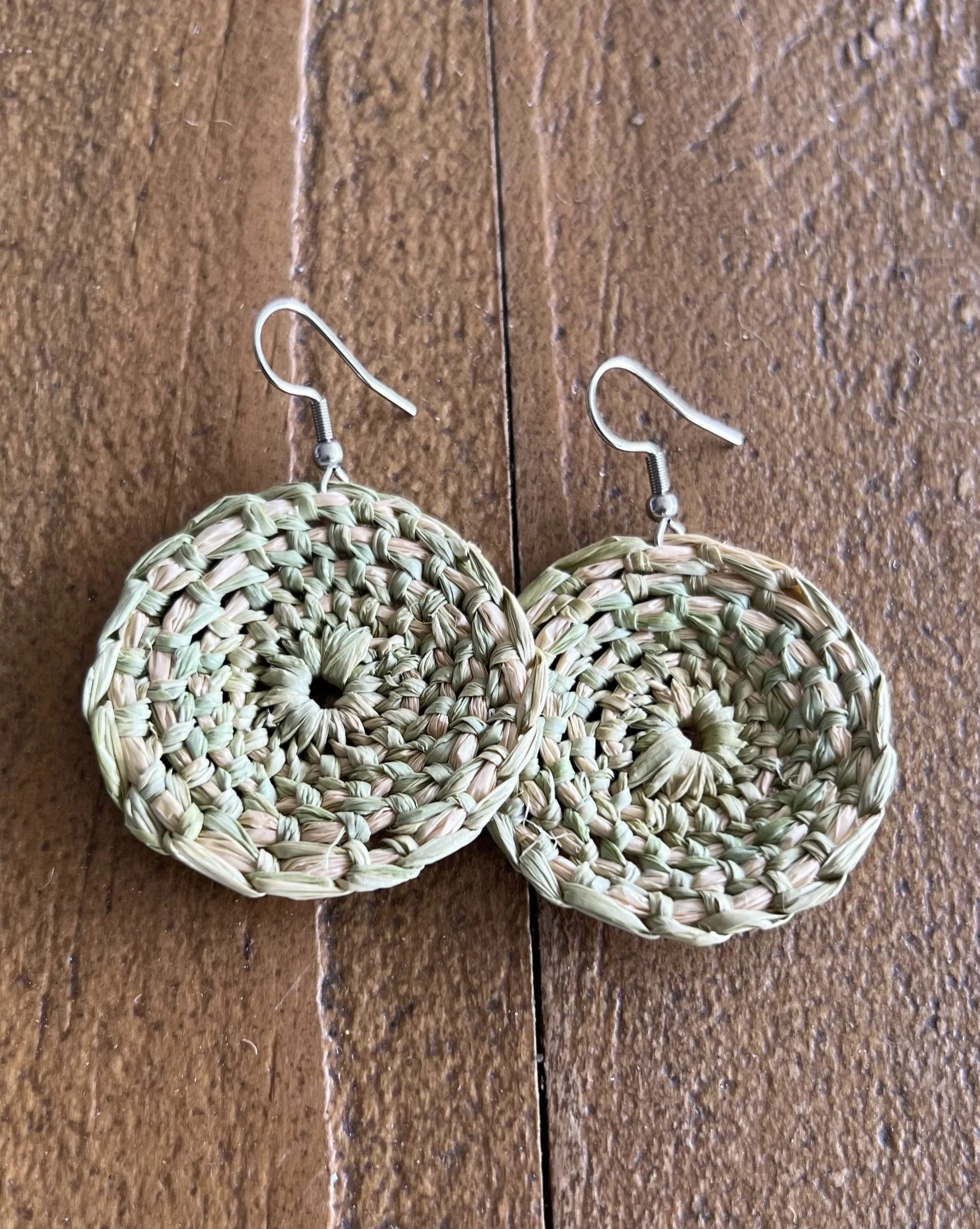 Pair of green circular woven earrings with hook clasps.