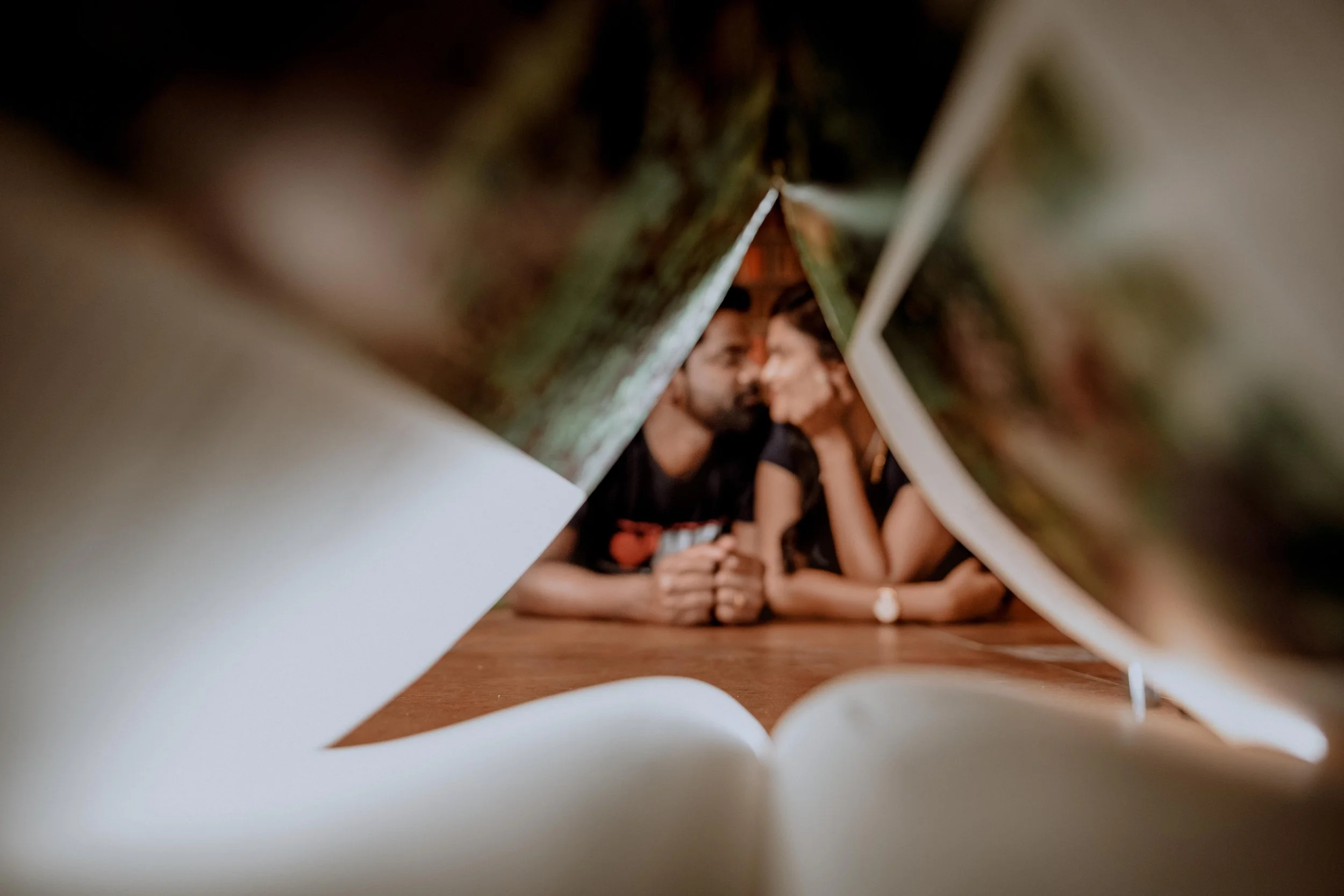 A photo of a couple seen through the opening of a cardboard box, with their faces close together, sharing an intimate moment.