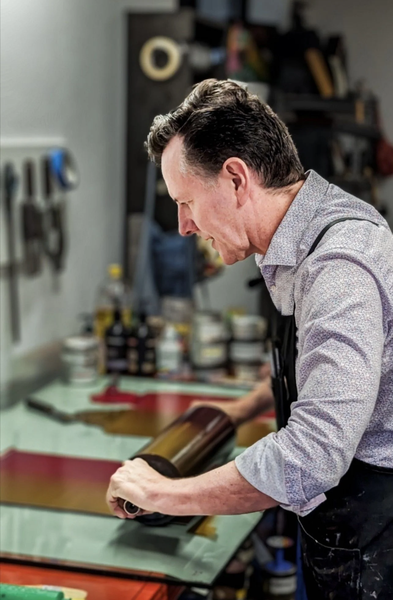 Man in apron working with glass in a workshop.