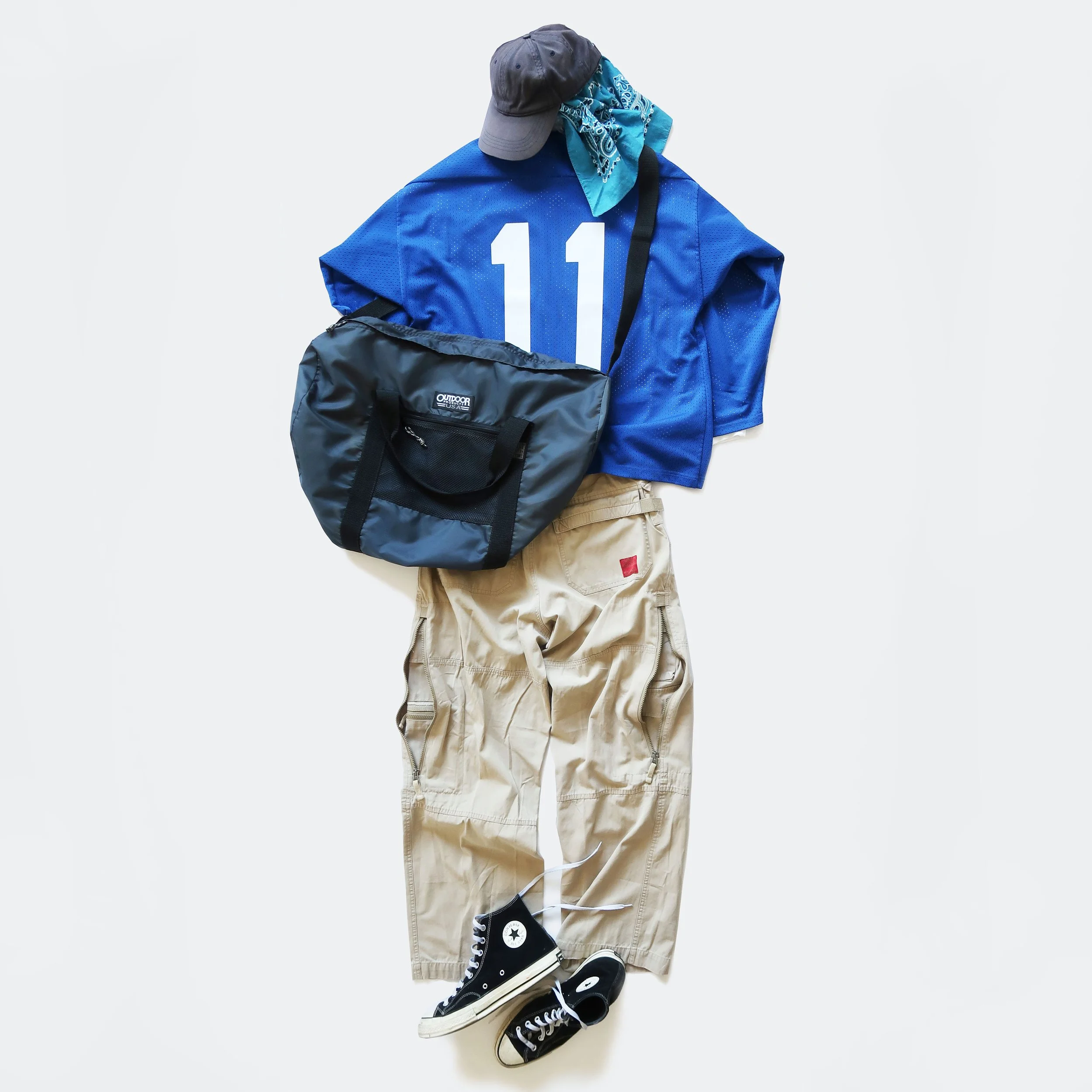 Casual outfit laid out on a white surface: gray hat, blue bandana, blue sports jersey with the number 11, khaki cargo pants, black high-top sneakers, black athletic bag.