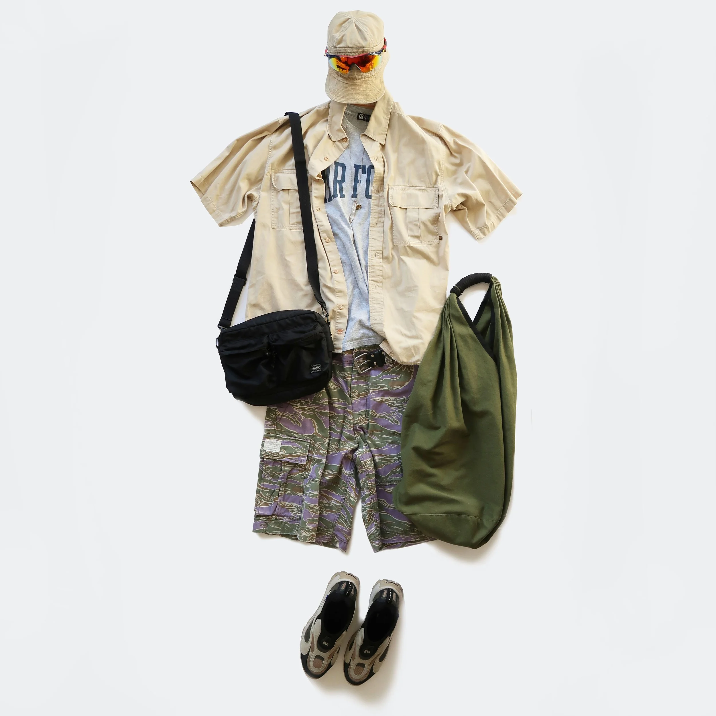 Clothing and accessories arranged on a white background, including a beige bucket hat, sports sunglasses, beige short-sleeve button-up shirt, gray T-shirt with the word 'FIRE', camouflage shorts, a black shoulder bag, green jacket, and a pair of athl