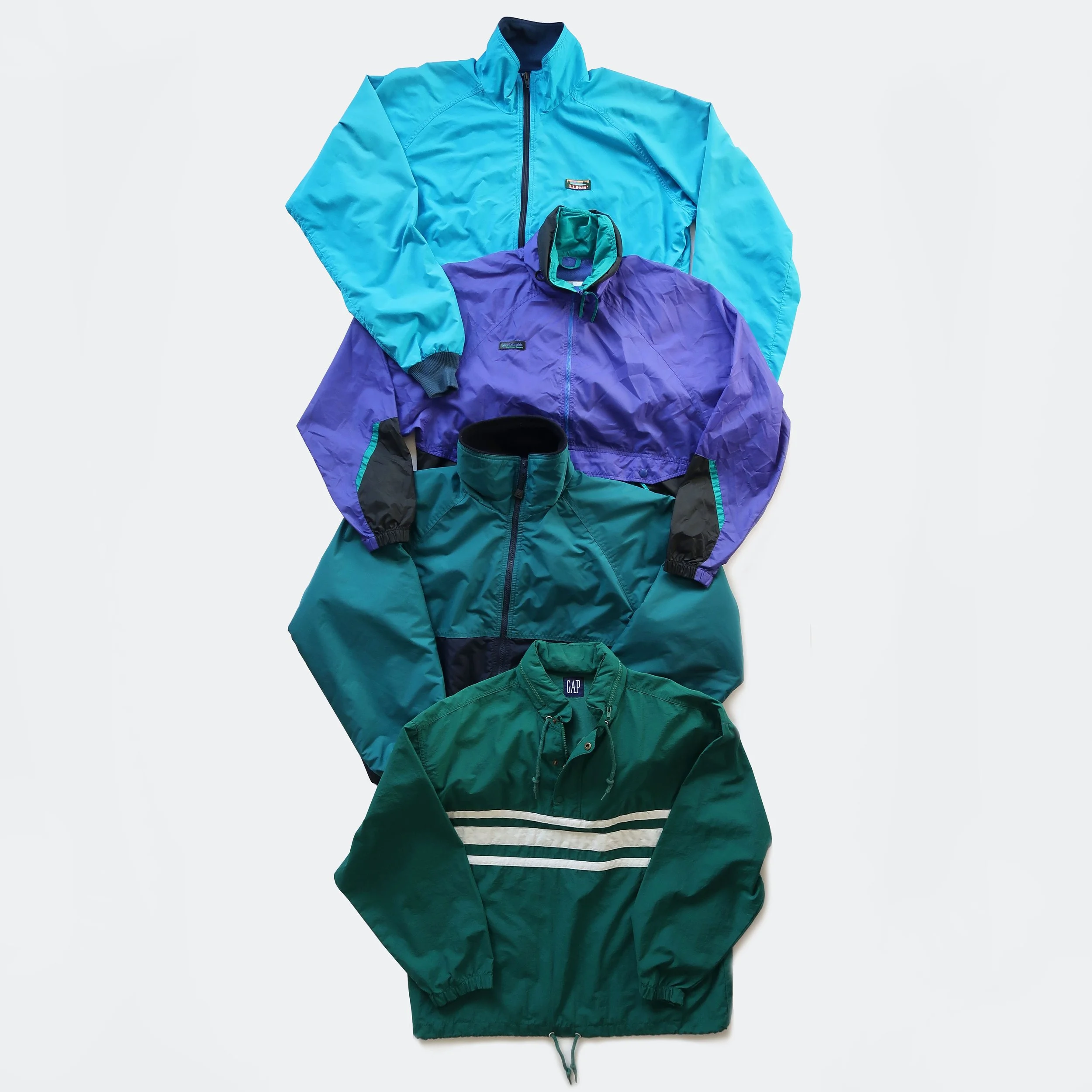 A collection of four colorful jackets and a striped shirt laid out on a white background.