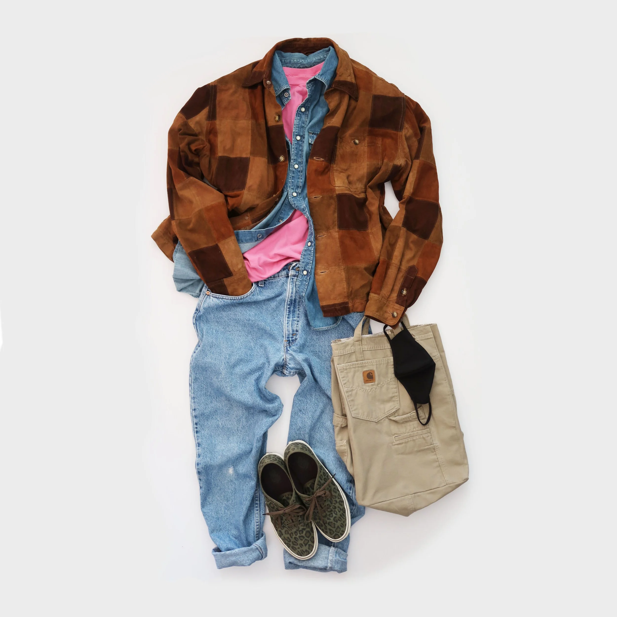 Casual men's outfit laid out on a white background, including a brown patchwork jacket, a denim shirt, a pink t-shirt, light blue jeans, patterned sneakers, and beige and black backpacks.