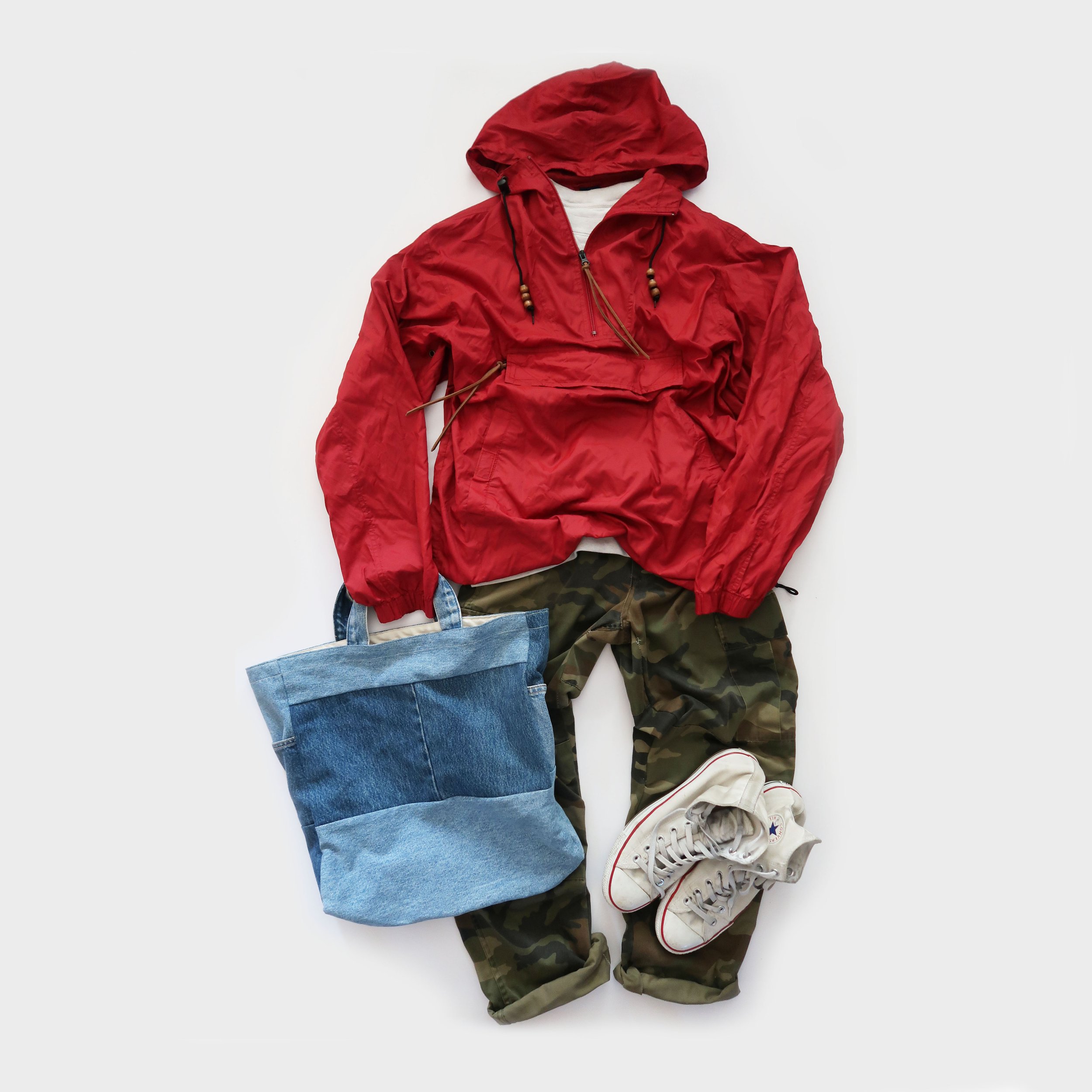 Red hooded jacket, camouflage pants, white sneakers, blue tote bag on white background.