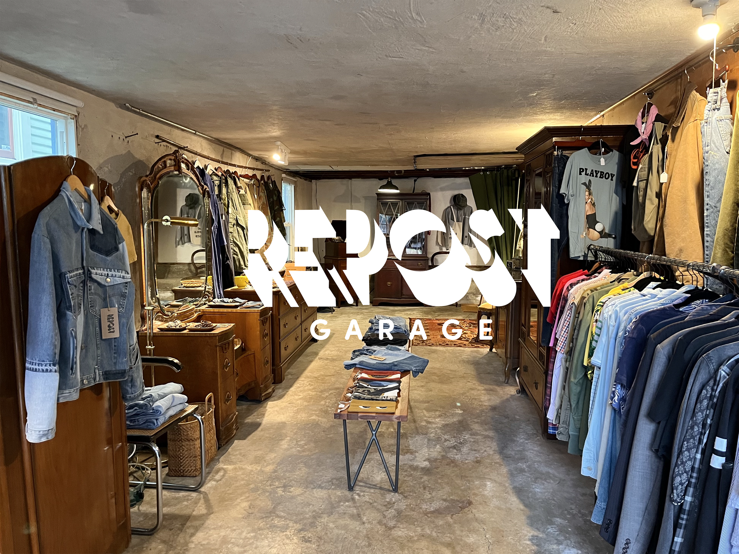Inside of a vintage store or garage clothing shop with wooden furniture, clothes on racks, and a sign with the words RE-POST GARAGE.
