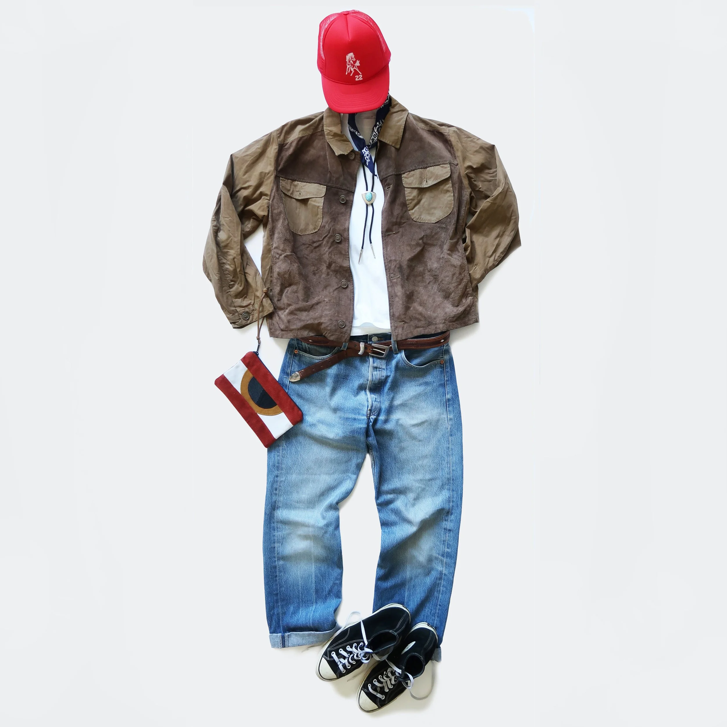 Casual outfit laid out flat with a red baseball cap, brown and beige jacket, white t-shirt, blue jeans, and black sneakers.
