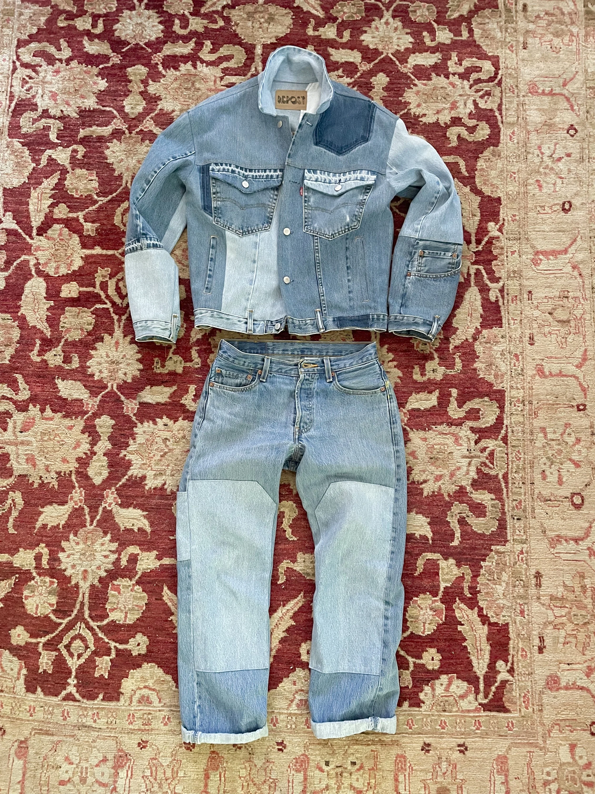 A denim jacket and a pair of jeans laid out on a red patterned rug.