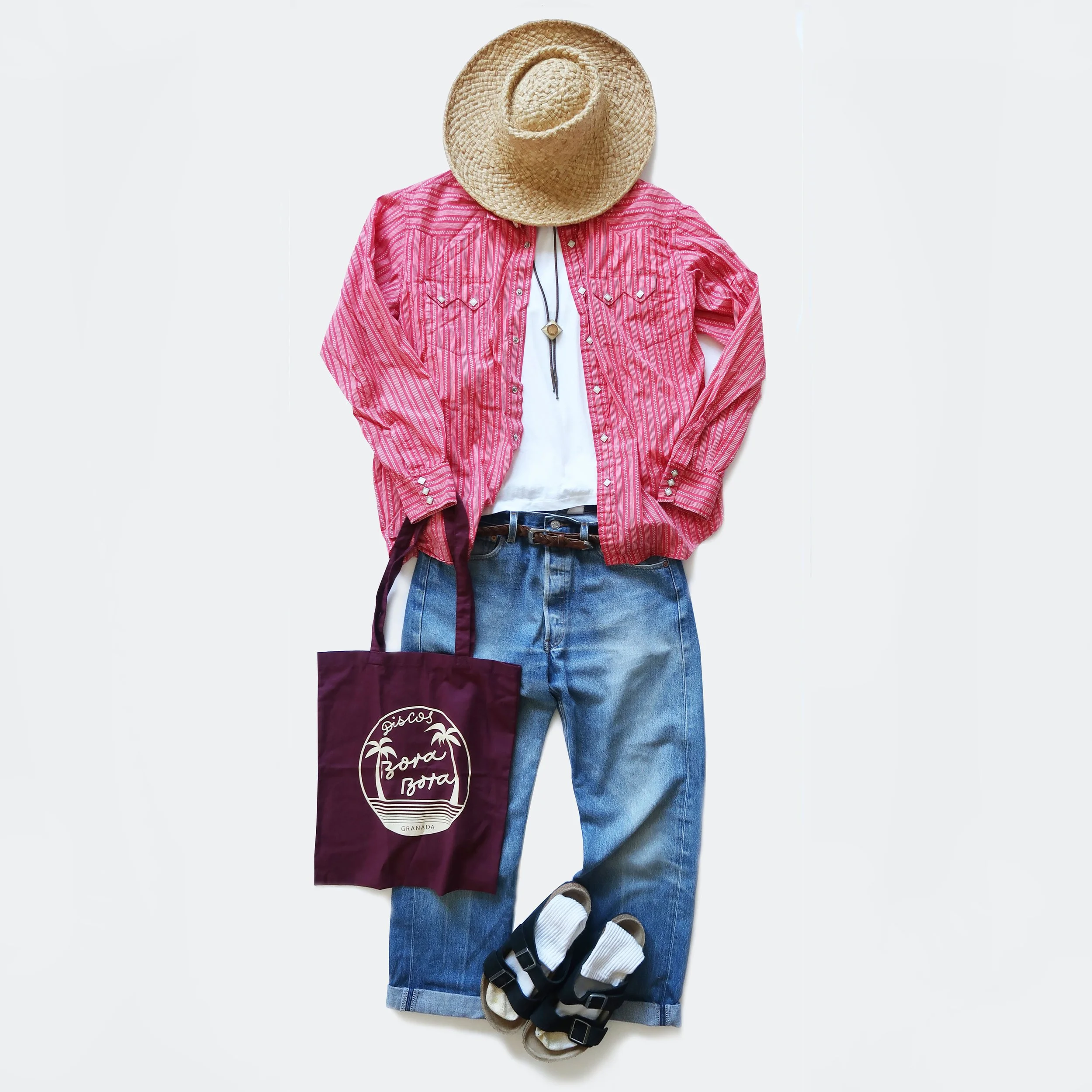 Casual outfit with a straw hat, pink striped shirt, white t-shirt, jeans, black belt, and folded socks.