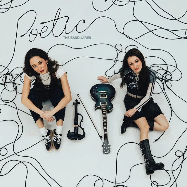 Two women sitting on the floor with a black electric guitar, a violin, and a bow between them, with a white background featuring black line art and the words 'Poetic' and 'The Band Jaren'.