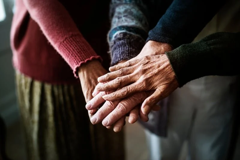 Three elderly hands crossing over