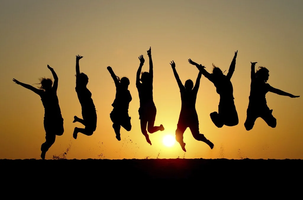Silhouettes of children jumping in the air during sunset