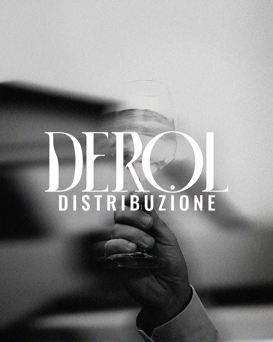 Black and white photo of a hand holding a glass, with text "DEROI DISTRIBUZIONE" overlaid.