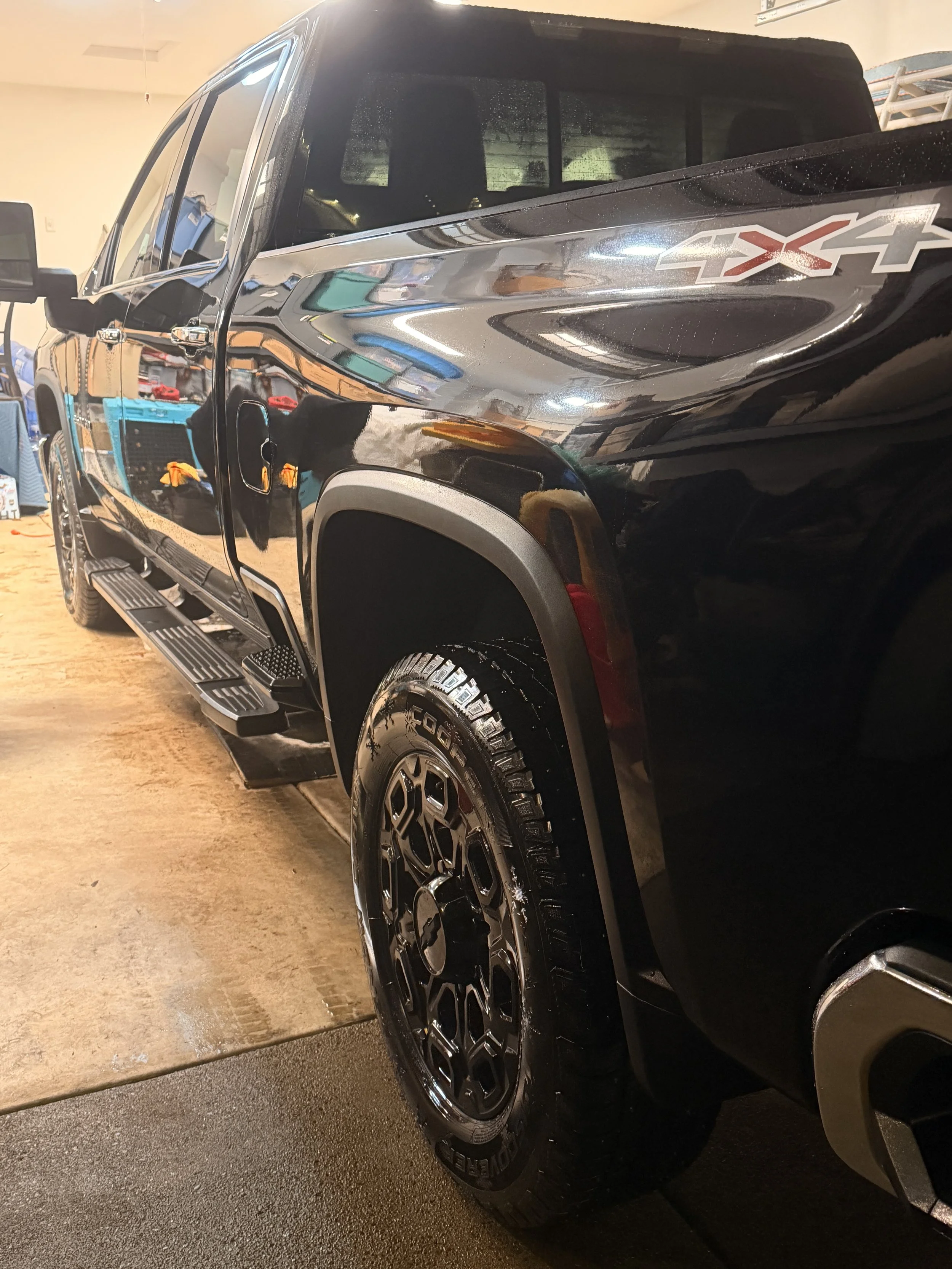 A black pickup truck with 4x4 decal on the front fender, parked inside a garage or workshop.