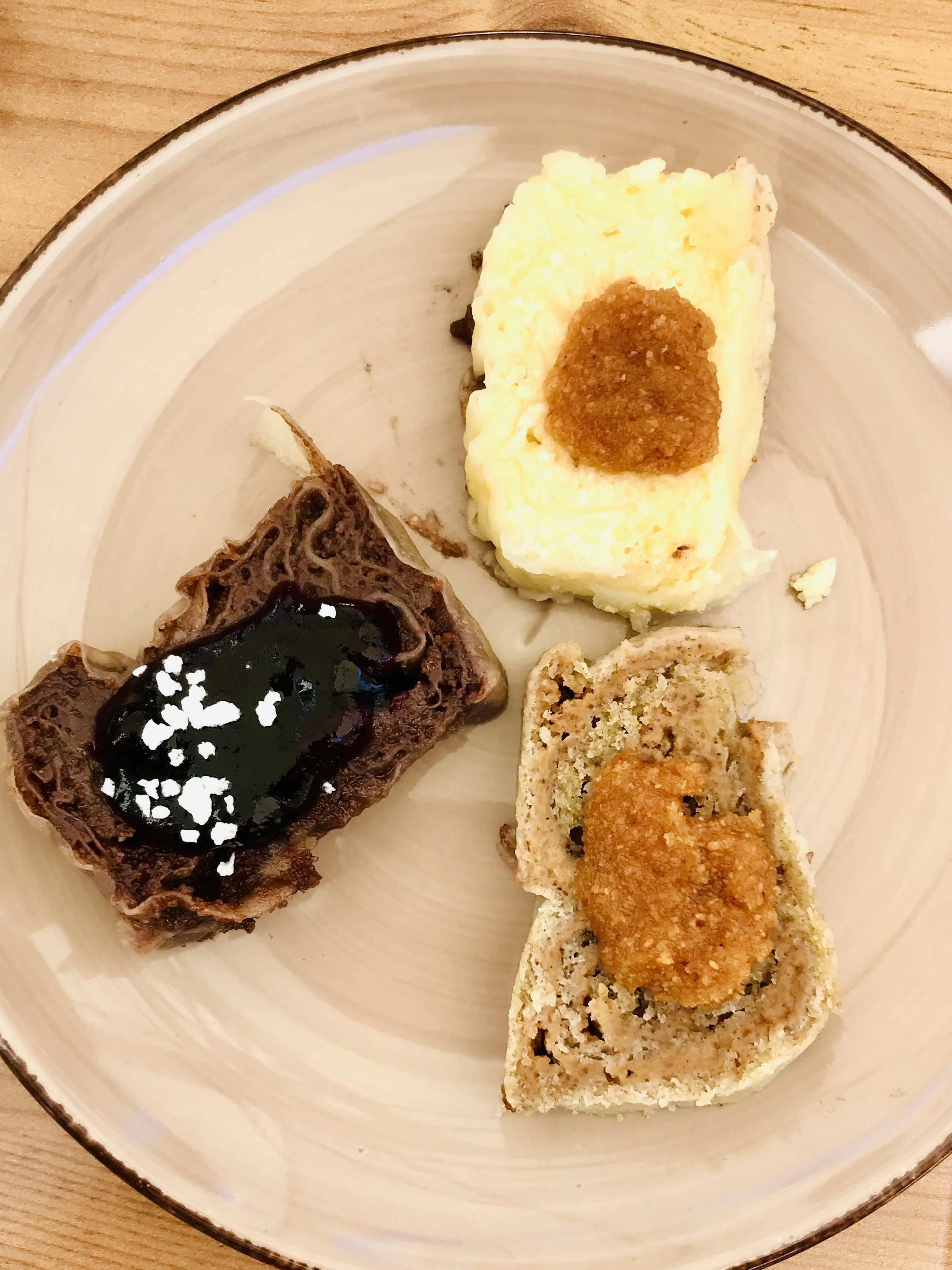 Sliced bread topped with fried chicken, biscuits with gravy, and a chocolate tart with blueberry sauce on a round plate.
