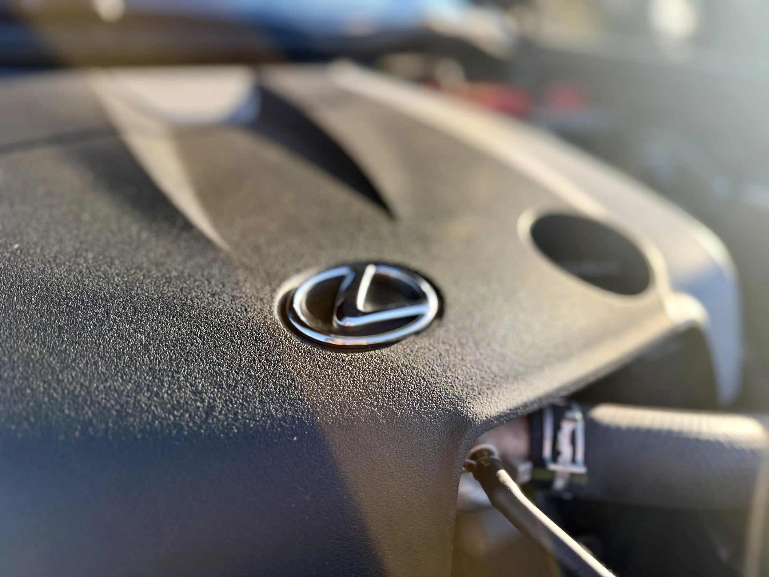 Close-up of a Lexus engine bay with the Lexus emblem in focus.