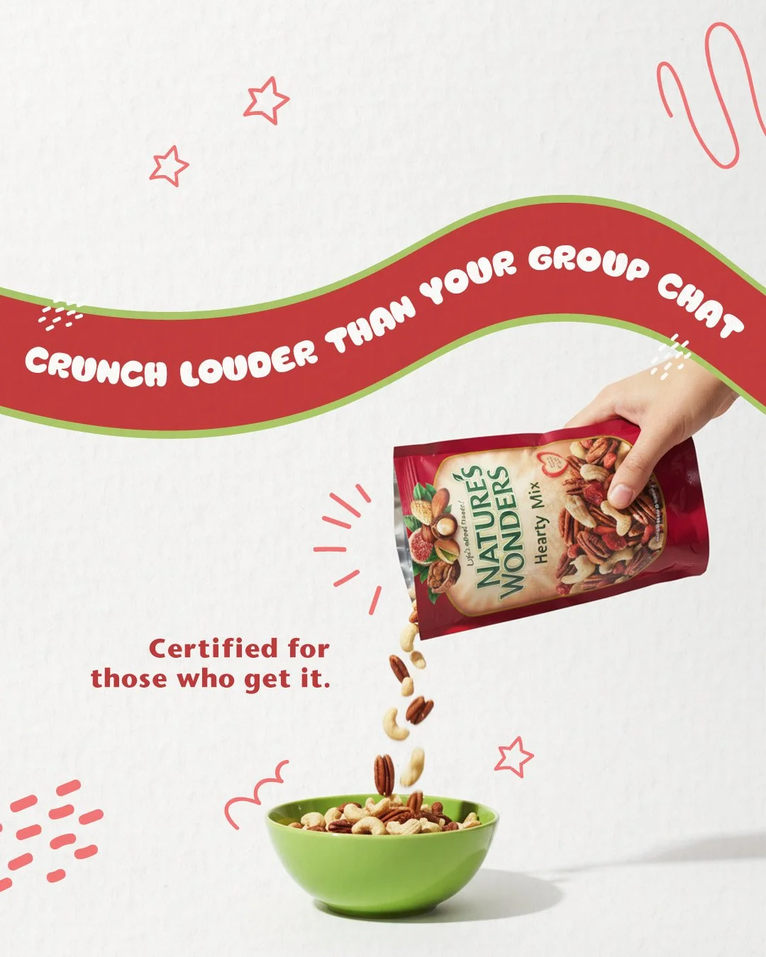 A hand pouring nuts from a red bag labeled 'Nature's Wonders Hearty Mix' into a green bowl. The background features a red and green wave with the text 'Crunch Louder Than Your Group Chat' and 'Certified for those who get it.' The design includes small star and line illustrations.