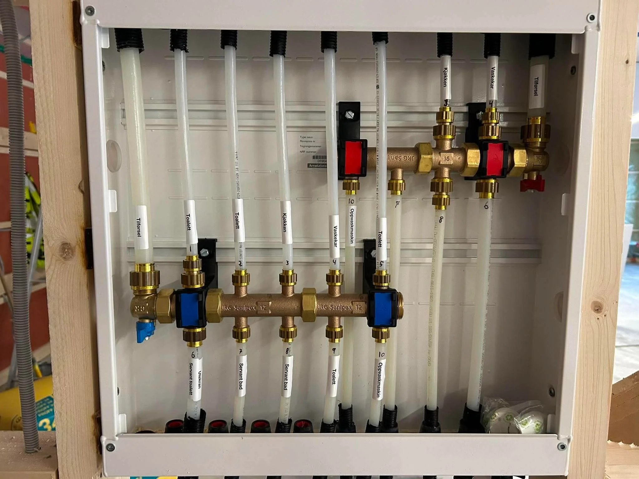 Et elektrisk varmekubbe med rørledninger og ventiler installert i et veggskap, brukt til oppvarming av en bygning.
