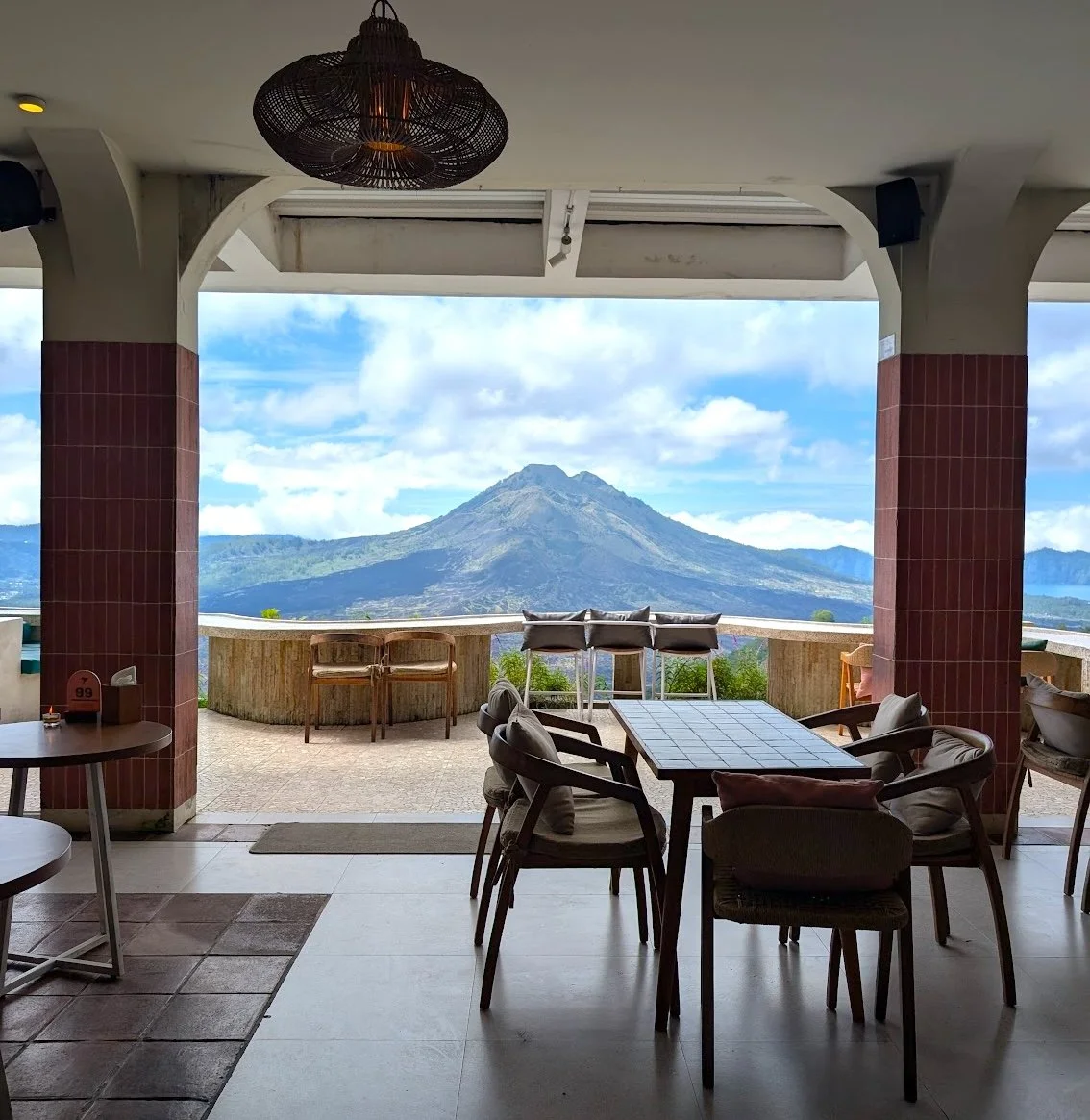 Indoor seating area with tables and chairs, overlooking Mt Agung Bali in the distance.