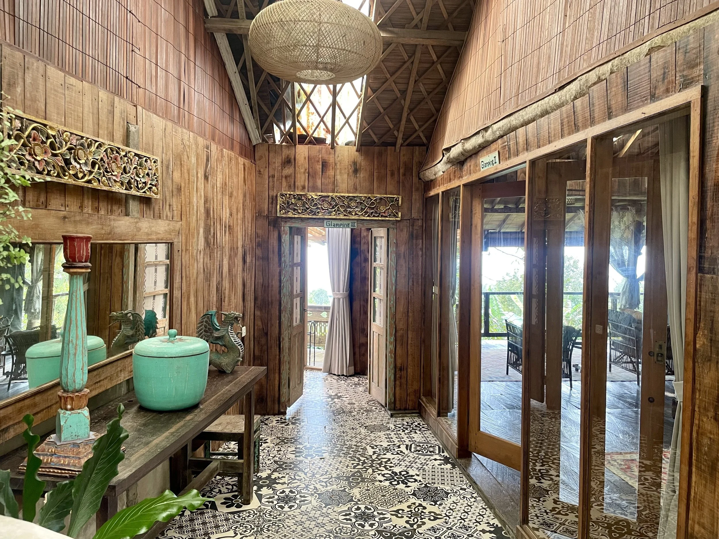 Wood-paneled interior with patterned tile floor, wooden decor, mirrors, and glass doors leading to an outdoor patio with seating.