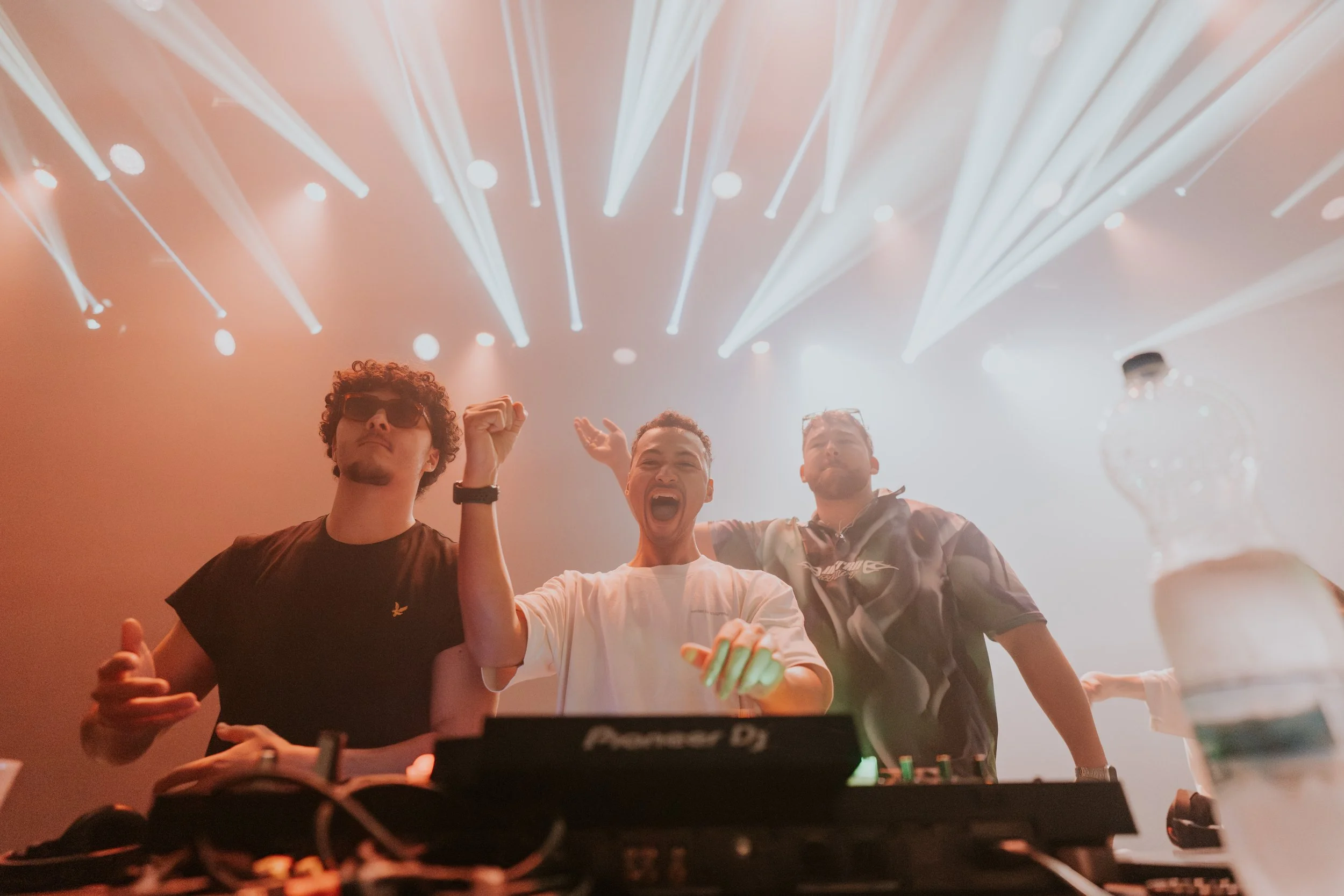 3 Jungs in Party-Stimmung hinter einem DJ Pult