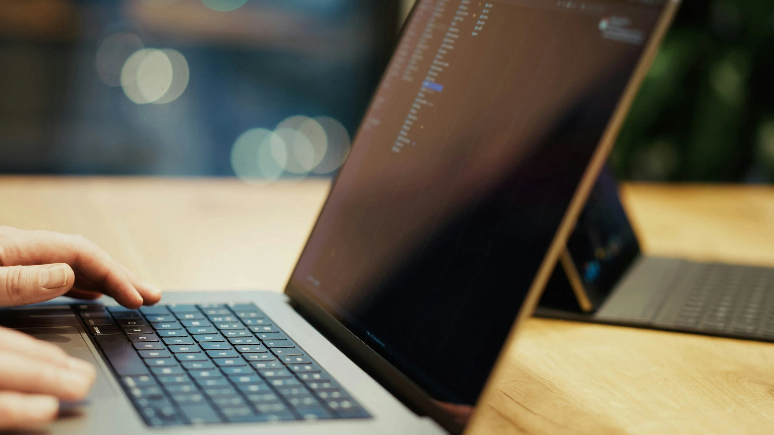 Close-up of a person using a laptop with a screen displaying lines of code.
