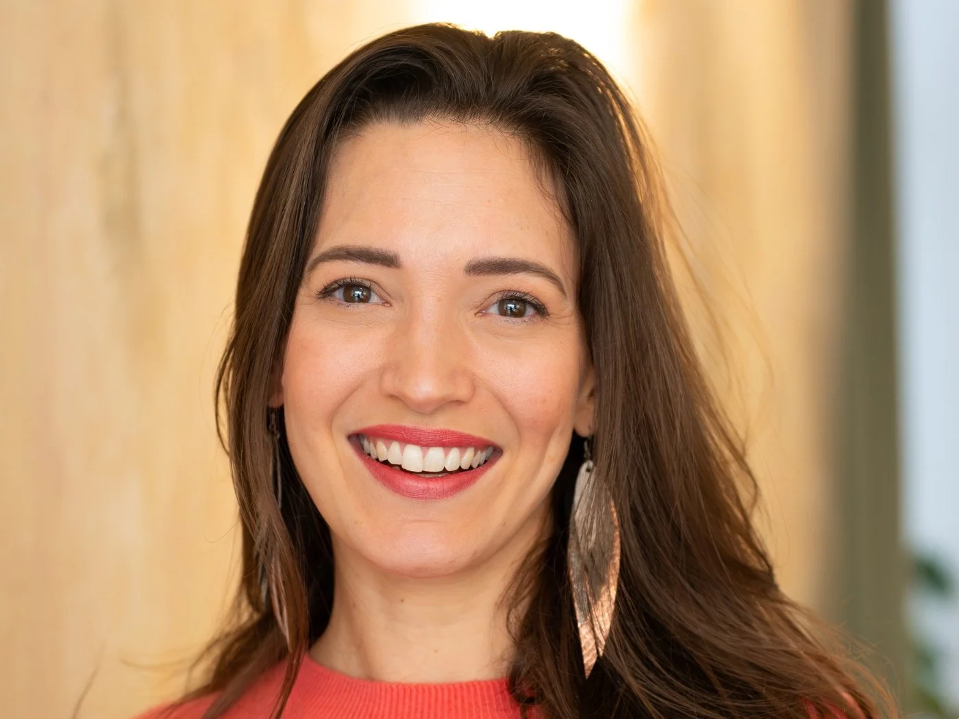 Ein lächelndes junges Frau mit braunen Haaren vor einem hellen Hintergrund.