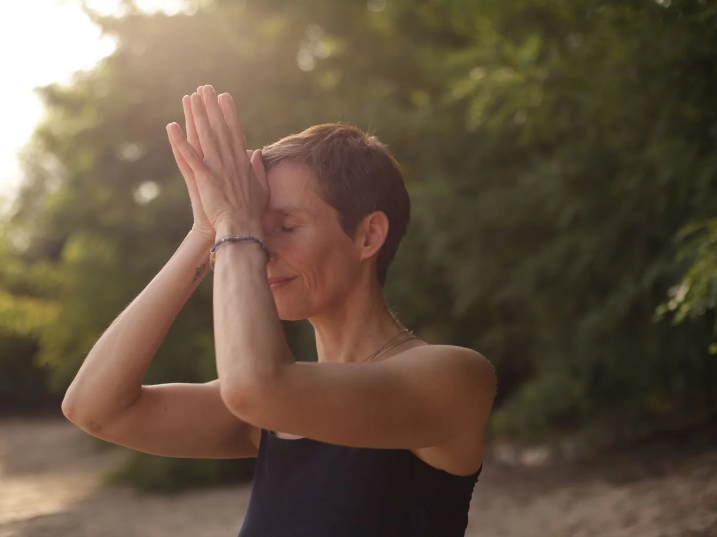 Frau beim Yoga im Freien, die Augen geschlossen hat und ihre Hände in Gebetshaltung vor das Gesicht hält.