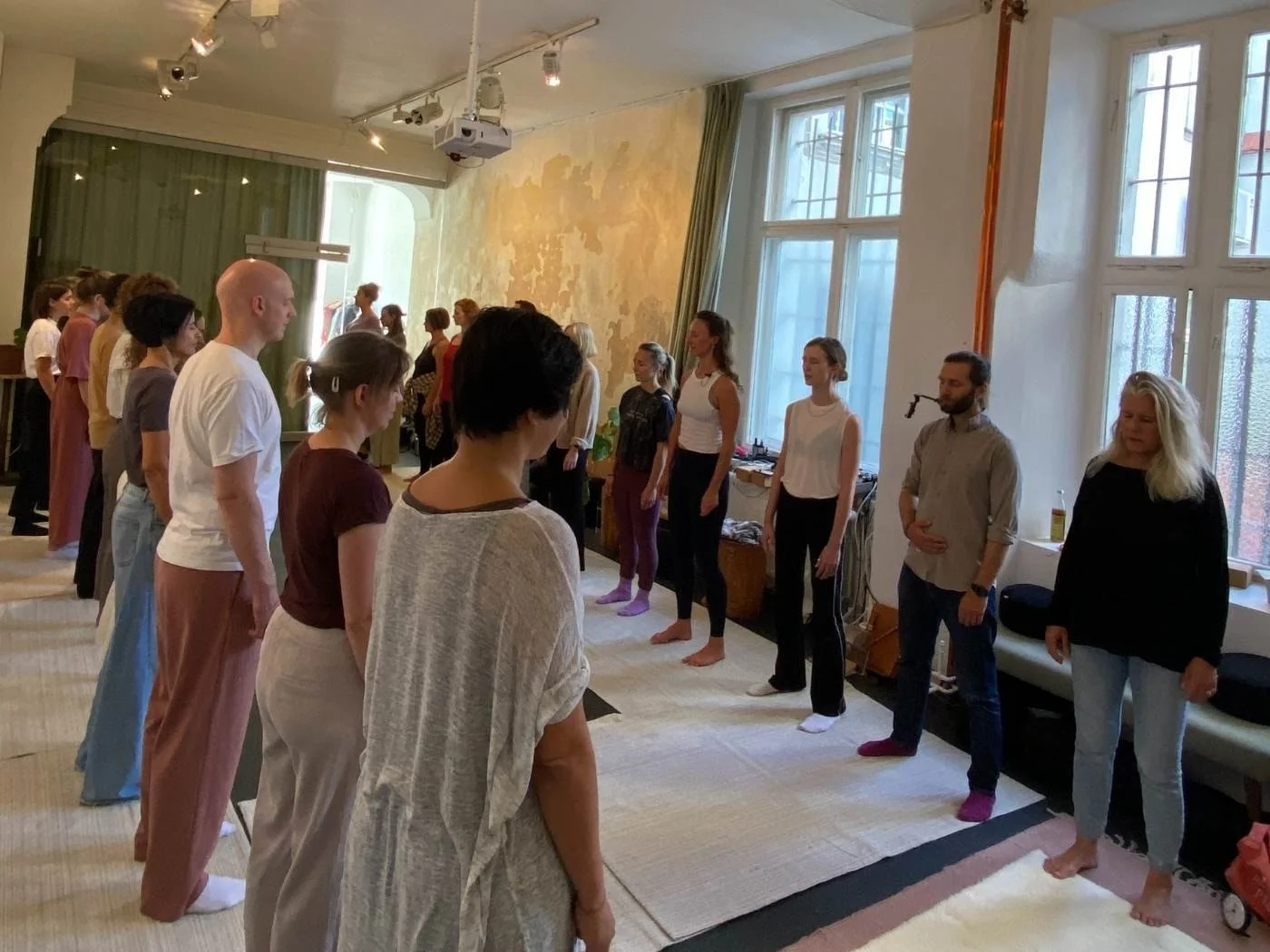 Menschen stehen in einer Yogastudio in einer Linie und erscheinen, sich auf eine Meditation oder eine Yogapraxis vorzubereiten.