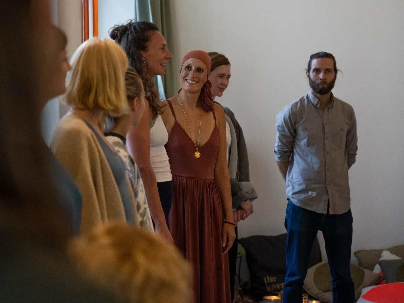 Eine Gruppe von Menschen steht in einem Raum, einige lächeln, während andere aufmerksam zuschauen.