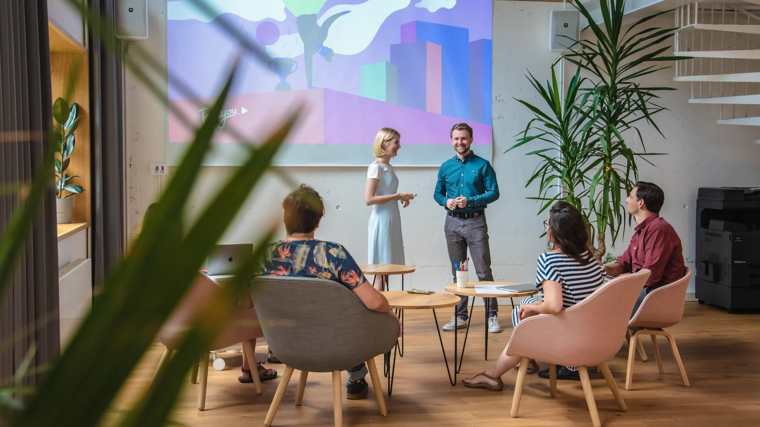 Skupina lidí na workshopu sledující prezentaci v moderním kreativním prostoru, firemní brand fotografie.