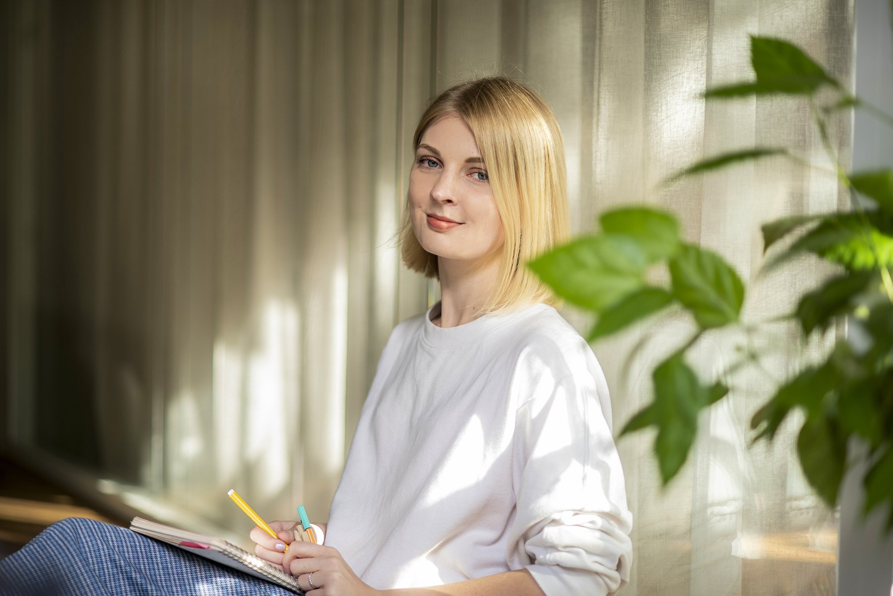Žena sedící u okna s poznámkovým blokem, profesionální lifestyle portrét vhodný pro osobní branding.