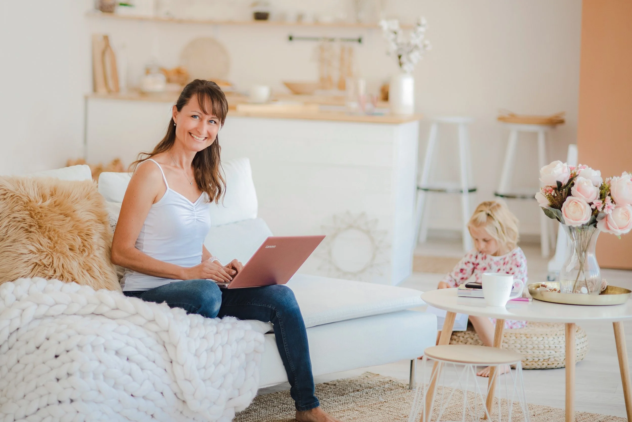 Žena sedící na gauči s notebookem v útulném interiéru, pracovní lifestyle foto vhodné pro freelancery a poradenské profese.